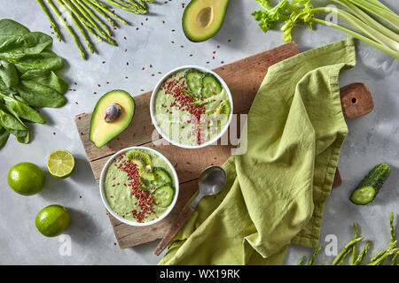 Green smoothies from avocado with cucumber, kiwi and flax in a plate on a wooden board on a gray concrete background. Healthy fo Stock Photo