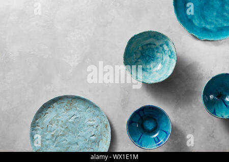 Porcelain blue bowls and plates on a gray marble table. Multi-colored ceramic vintage handmade dishes Stock Photo