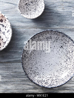 Set of handcrafted porcelain bowls on a gray wooden table. Vintage painted plates dishes. Flat lay. Stock Photo
