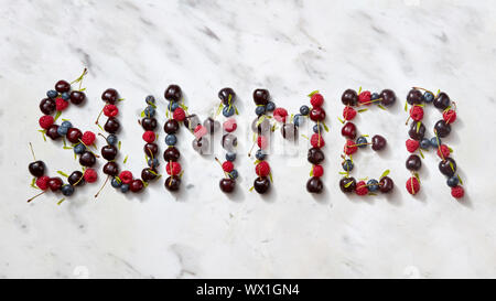 Summer background with summer berries - word SUMMER from cherry, raspberry, blueberries on gray stone background. Stock Photo