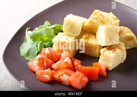 still life spanish omelette with tomato on brown plate Stock Photo