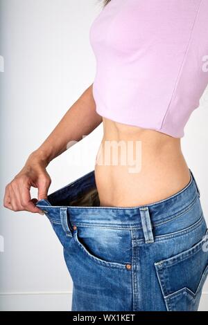 Young slim woman, close-up of tanned stomach, navel, hips, chest, wearing  jeans, lying on towel Stock Photo - Alamy