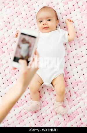 sweet baby girl being photographed by smartphone Stock Photo