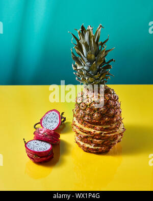 Tropical Pineapple fruit single whole and dragon fruit, pitaya made up of sliceson on a duotone yellow-green background Stock Photo