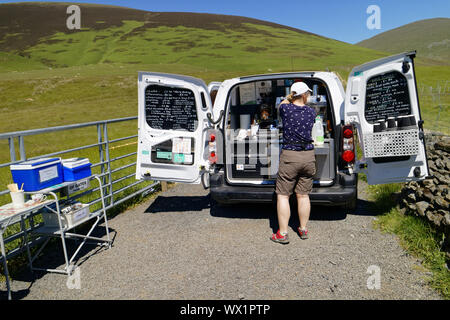 A lady selling coffee, tea and snacks to hikers from the back of a well equipped van Stock Photo