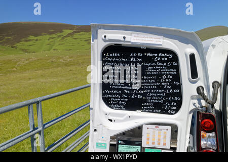 A lady selling coffee, tea and snacks to hikers from the back of a well equipped van Stock Photo