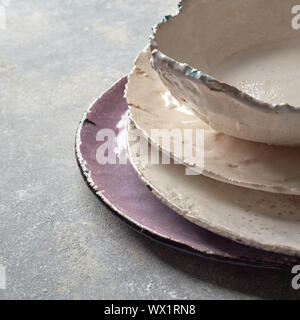 Decorative handcrafted pottery - bowls, plates covered with glazed on a gray background with place for text. . Stock Photo