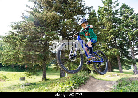 A seven year old boy doing jumps on his mountain bike