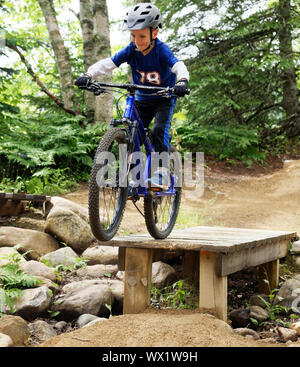 A seven year old boy on his mountain bike practicing drop-offs in a skills park Stock Photo