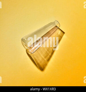 A transparent glass vase empty lies on a yellow paper background with soft shadows Stock Photo
