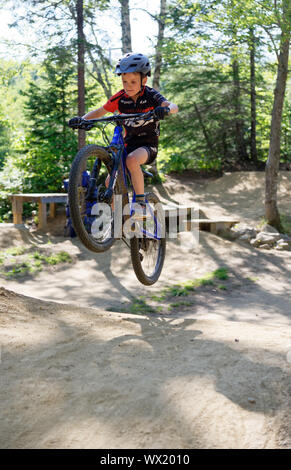 A seven year old boy doing jumps on his mountain bike