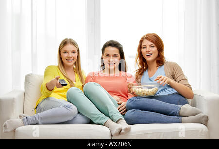 teenage girls or friends watching tv at home Stock Photo