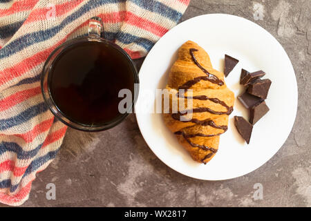 Cup of coffee and chocolate croissant on a gray background. Top view. Breakfast concept Stock Photo