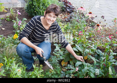 A woman is gardening in the front garden of her house Stock Photo