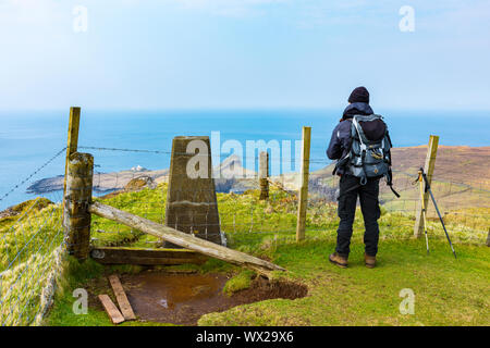 A walker at the summit trig point on Waterstein Head, Duirinish, Isle of Skye, Scotland, UK Stock Photo