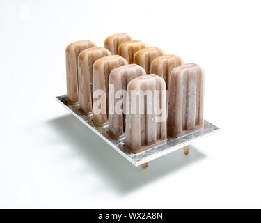 Coffee ice cream. Plastic molds with homemade ice cream on a stick on a white background with reflection of shadows. Copy space Stock Photo