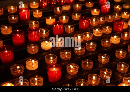 rows of lit church candles on a votive Stock Photo