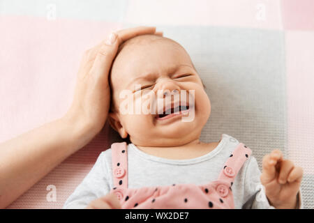 mother's hand touching crying little baby daughter Stock Photo