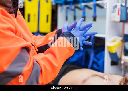 Emergency doctor putting on gloves in ambulance Stock Photo
