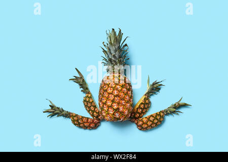 Food composition of a whole and pieces of pineapple on a blue ba Stock Photo