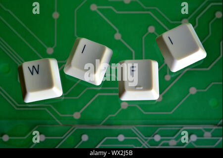 Keyboard keys form the word WI FI on green electric circuit in the background. Stock Photo