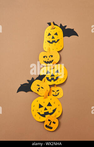 Different handcraft scary pumpkins and bats on a brown background with space for text. Creative composition for Halloween. Flat Stock Photo