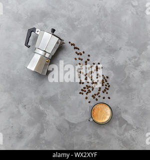Aromatic coffee beans in the form of a pouring drink from italian metal coffee maker on a gray background with copy space. Flat Stock Photo