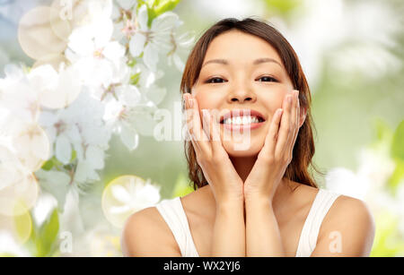happy smiling young asian woman touching her face Stock Photo