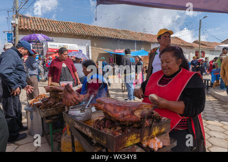 Woman selling fried meat at an open air stall. Very busy Sunday market in Tarabuco, department Sucre, Bolivia, Latin America Stock Photo