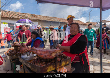 Woman selling fried meat at an open air stall. Very busy Sunday market in Tarabuco, department Sucre, Bolivia, Latin America Stock Photo