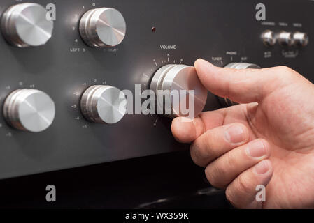 Hand turning up the volume in a stereo Stock Photo