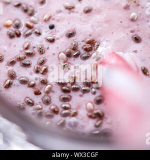 Macro photo appetizing milky berry smoothie with organic chia seeds in a glass with a straw. Healthy dessert. Top view Stock Photo
