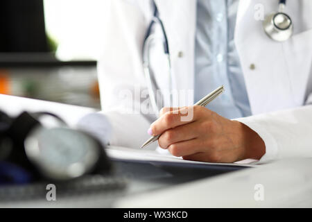 Hands of female GP making notes with silver pen Stock Photo