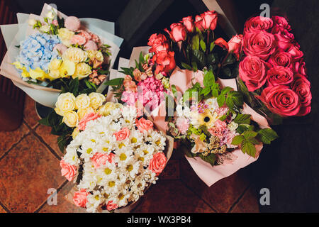 Bouquets of flowers on the floor in front of a flower shop with lilies, sunflowers, carnations, statices, and more Stock Photo