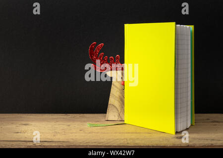 a yellow green note book with hidden reindeer on a wooden table Stock Photo
