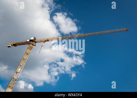 Tower crane under the blue sky. Yellow crane on construction site under a fluffy white cloud Stock Photo