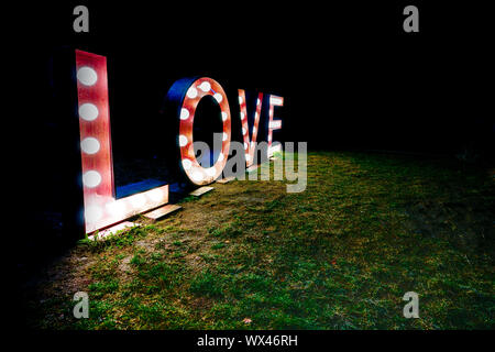 black night with the word and text love written in brightly lit letters Stock Photo
