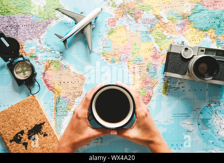 Top view of young woman planning her vacation using world map while drinking coffee - Tourist pointing the next travel destination Stock Photo