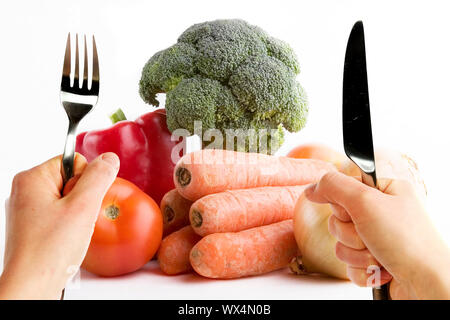 Group of raw vegetables on a white background with two hands in the foreground very eager to eat the food. Stock Photo