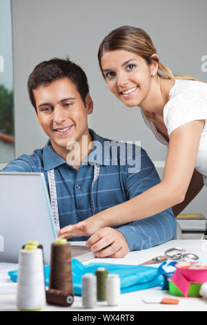 Portrait of young female fashion designer assisting man while working on laptop Stock Photo