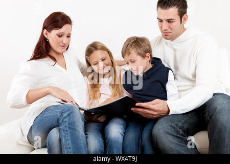 Hapy young family watching photo album at home Stock Photo