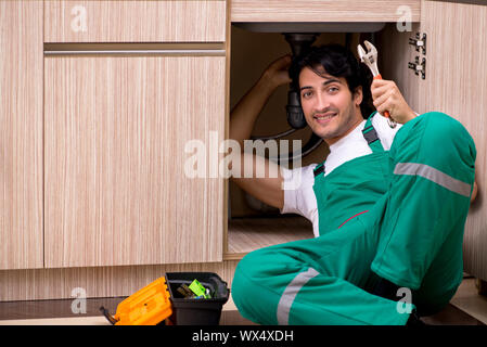 Young plumber repairing wash basin at kitchen Stock Photo