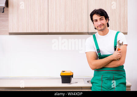 Young plumber repairing tap at kitchen Stock Photo