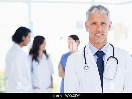 Mature doctor standing upright in front of his interns Stock Photo