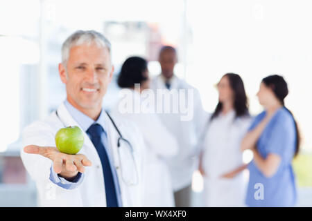 Smiling mature doctor holding an apple Stock Photo