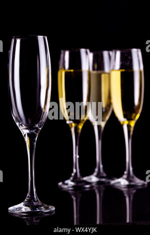 Three full glasses of champagne and one empty against black background Stock Photo