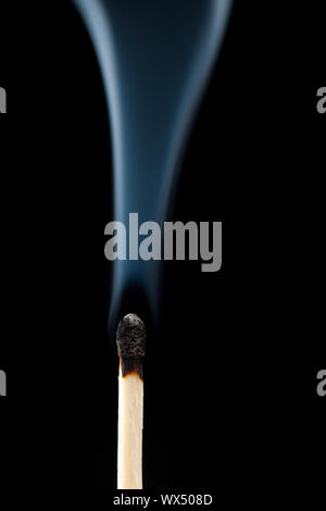 Smoking consumed match against a black background Stock Photo