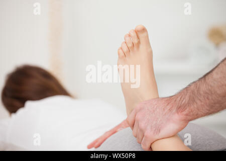 Woman lying forward while a physio manipulates her foot in a room Stock Photo