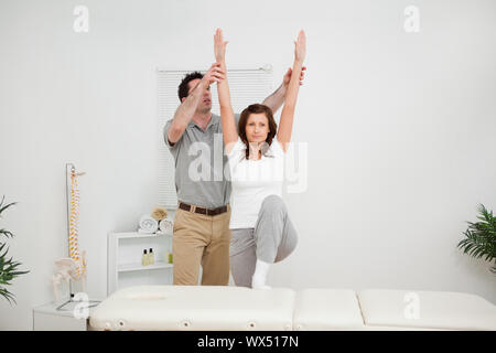 Brunette doing stretching exercises with a physiotherapist in a room Stock Photo
