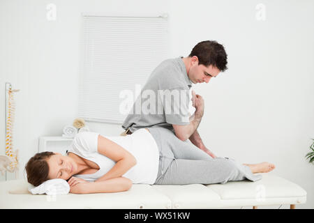 Chiropractor massaging the thigh of his patient while using his elbow in a room Stock Photo